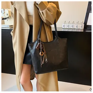 Dettaglio borsa shopper retrò marrone scuro con ciondolo a cioccolato sulla spalla