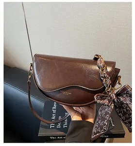 Detail view of dark brown saddle bag with glossy finish and silk scarf decoration