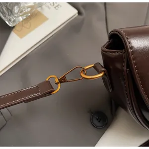 Detail of vintage bronze hook and fine stitching on dark brown leather saddle bag