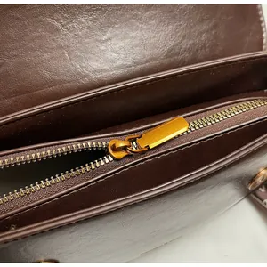 Macro shot of durable bronze metal zipper and smooth dark brown leather texture of bag