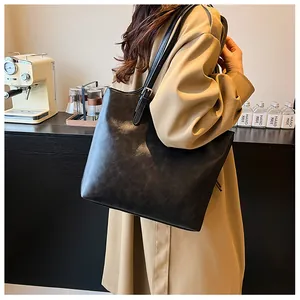 Vista dettagliata della grande borsa tote nera vintage indossata a spalla su un trench