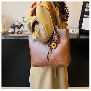 Dettaglio borsa tote in pelle marrone scuro con ciondolo a forma di ciambella sul manico