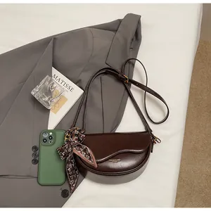 Detailed view of brown saddle bag with golden lettering and stylish heart pattern silk scarf