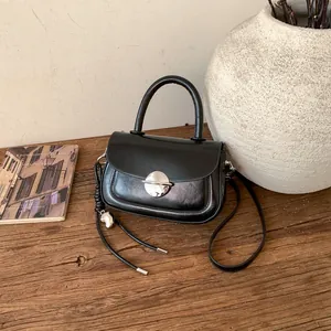 Detail of a vintage black saddle bag with silver buckle on a wooden desk with props