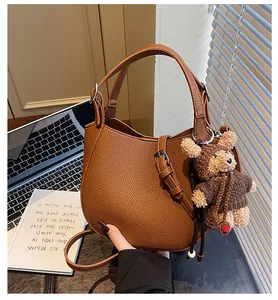 Detail of brown lychee leather hobo bag with a cute bear charm and adjustable strap