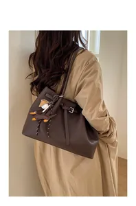 Detalle de bolso tote de cuero marrón oscuro con colgante de perro y textura
