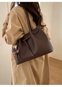 Detalle del bolso tote de cuero marrón oscuro con hebilla metálica y colgantes creativos