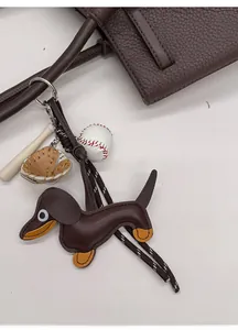 Detalle de colgante de perro salchicha en cuero con mini accesorios de béisbol