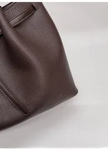 Primer plano de la textura de cuero de grano litchi marrón oscuro en un bolso tote elegante