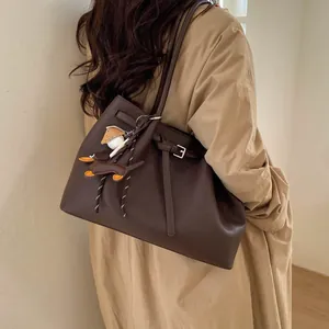 Bolso tote de cuero marrón con hebilla de cinturón decorativa y colgante de animalito
