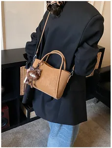 Detail of caramel faux leather bucket bag with furry charm on a casual model outfit
