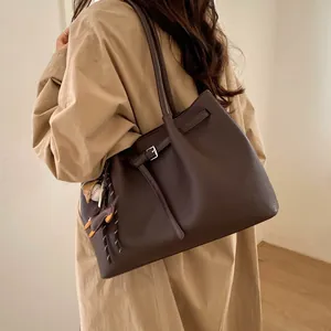 Detalle de bolso tote grande de cuero marrón café con hebilla plateada y colgante de animal