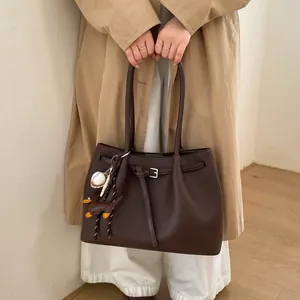 Detalle del bolso tote de cuero marrón oscuro con hebilla plateada y colgante de teckel