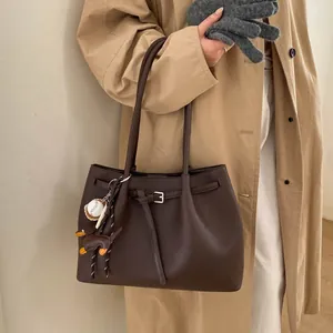 Detalle de bolso tote de piel granulada marrón oscuro con bonitos colgantes decorativos