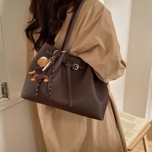 Detalle del bolso tote marrón oscuro en cuero texturizado con lindos colgantes