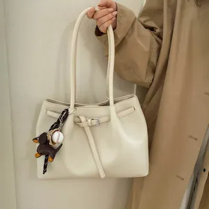 Detalle del bolso tote crema con elegante colgante de teckel y hebilla metálica