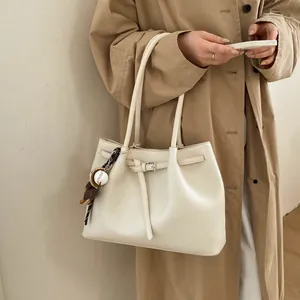 Bolso tote crema elegante con hebilla decorativa y amuleto de béisbol en una modelo
