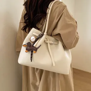 Detalle del bolso tote blanco crema con textura de lichi y colgante de perro teckel