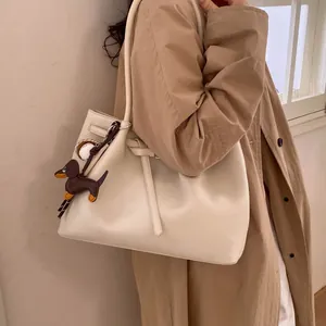 Detalle del bolso tote de cuero granulado crema con colgantes de teckel y béisbol