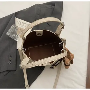 Top view of beige bucket bag showing interior space with cute brown teddy bear pendant