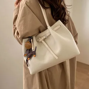 Detalle de bolso tote en cuero granulado blanco con elegante colgante de perro salchicha