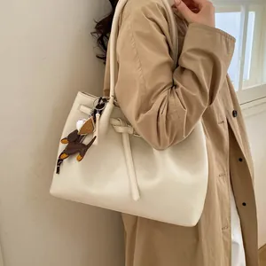 Detalle del bolso tote crema grande con textura litchi y colgante de perro decorativo