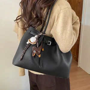 Detalle de bolso tote de cuero negro con colgantes decorativos llevado por una modelo