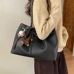 Primer plano del bolso tote de cuero negro con un colgante de perro teckel marrón