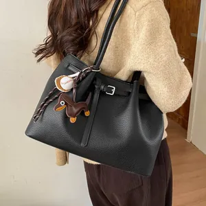 Detalle del bolso tote de cuero negro con hebilla plateada y colgante de perro