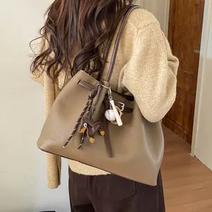 Detalle de bolso tote marrón con textura de cuero granulado y colgante de perro