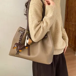 Detalle del bolso tote de cuero granulado marrón con dijes de perro salchicha y béisbol