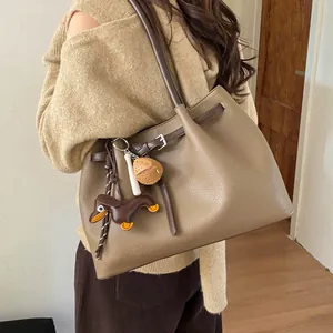 Detalle del bolso tote con textura de cuero litchi y colgante de dachshund marrón