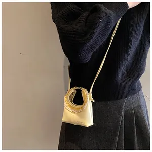 Detail of light yellow mini crossbody bag with ruffle lace handle and brand logo