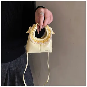 Detail of yellow mini shoulder bag with lace trim and silver HELAHE logo lettering