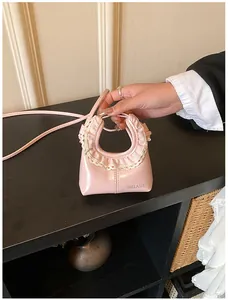 Close-up of a pink crescent bag featuring delicate cream lace trim and logo detail