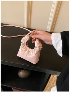 Detail of light pink mini bag with delicate white lace trim and thin shoulder strap