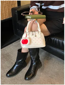 Detailaufnahme der weißen Muscheltasche mit roten Punkten und Herz-Anhänger-Zubehör