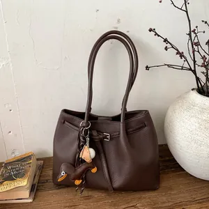 Detalle del bolso tote de cuero lichi marrón café con asas largas y colgante de perro