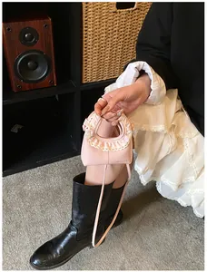Close-up of pink leather mini bag featuring beige lace trim and HELAHE branding