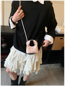 Close-up of pink patent leather crossbody bag featuring white lace trim and brand logo