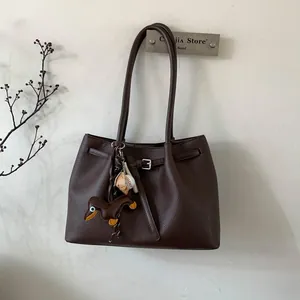 Detalle de bolso tote marrón oscuro en cuero granulado con bonitos colgantes de perro