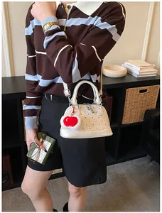 Detail der weißen Muschel-Handtasche mit roten Punkten und Herzanhänger als Umhängetasche
