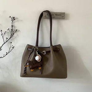 Detalle de bolso tote marrón café con amuleto de perro salchicha y guante de béisbol