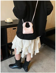 Detailed view of pink shoulder bag with ruffled edges and silver logo on glossy leather