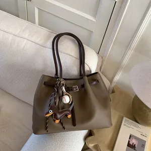 Detalle del bolso tote de cuero granulado caqui con un lindo colgante de perro teckel