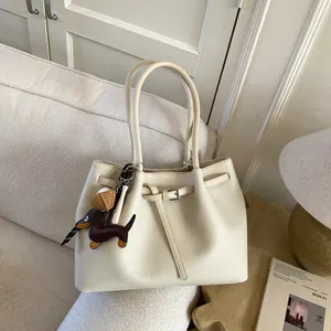 Detalle de la textura del bolso tote blanco crema con grano y colgante de perro