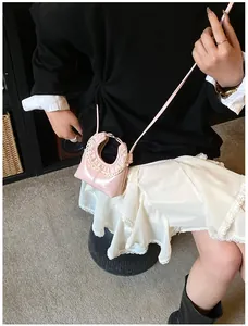 Close-up of pink glossy mini bag featuring white lace trim and metallic ring handle