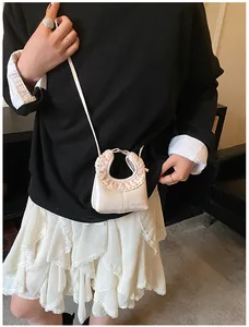 Detail of a cream-colored handbag with pink lace floral ruffle trim and shoulder strap