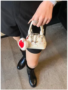 Detailed top-down shot of a cream shell bag with red polka dots and a cute apple charm