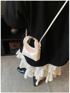 Close-up of creamy white faux leather mini bag with pink lace trim and brand logo